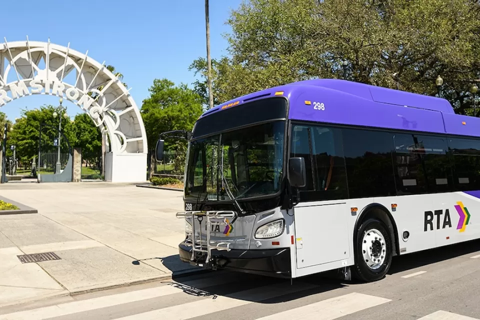 White and purple RTA bus inf ront of white archway to Armstrong transit station in New Orleans, Louisiana.